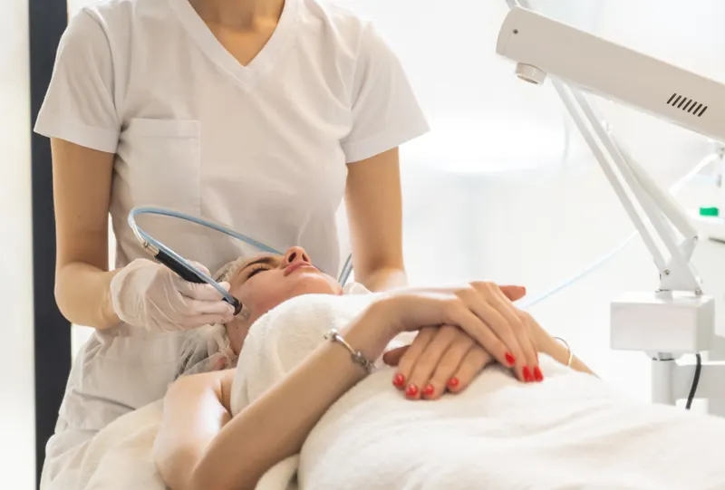 Aesthetician performing a treatment in a bright medical spa
