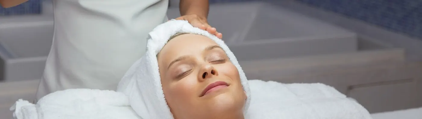 Client relaxing with a towel wrap during a facial