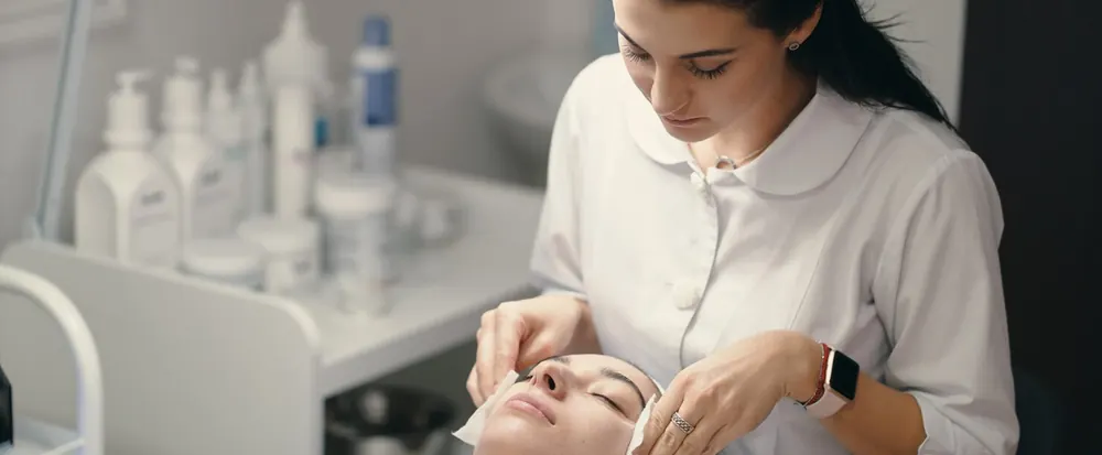 Esthetician cleansing a client's face during a customized facial