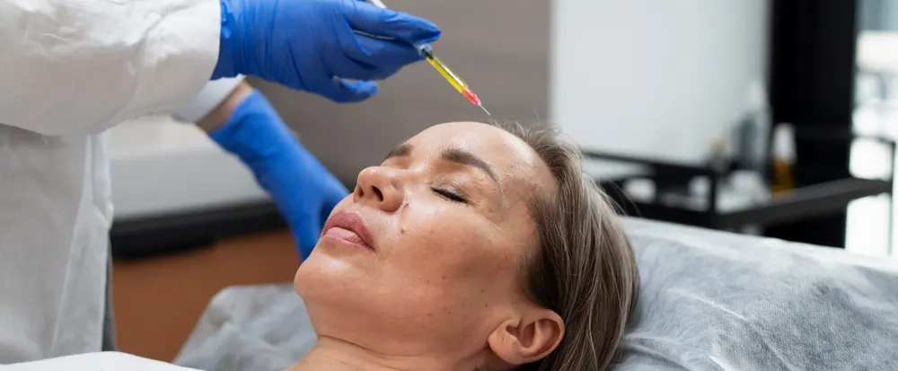 Provider applying an exosome treatment to a client's forehead