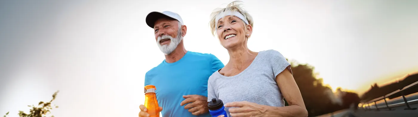 Active mature couple jogging outdoors at sunset