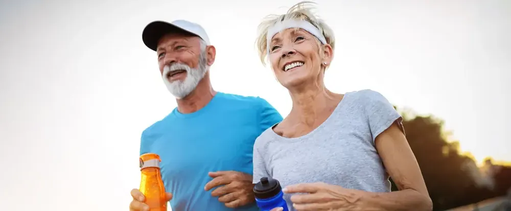 Active mature couple jogging outdoors at sunset