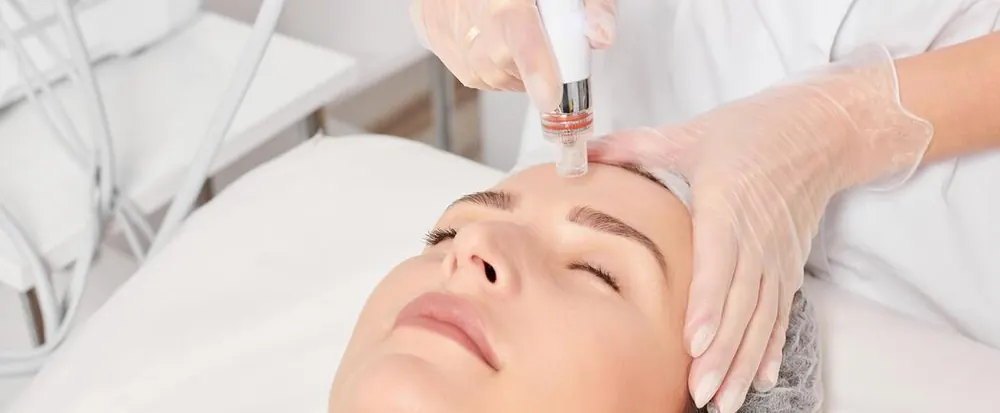Meso needling pen being used on a client's forehead