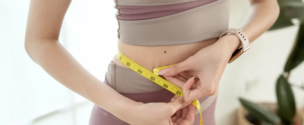 Woman measuring her waist with a tape measure