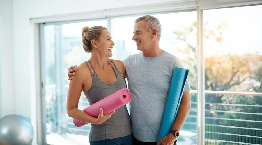 Smiling couple holding yoga mats after a workout